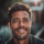 Homme souriant avec fond flou naturel.